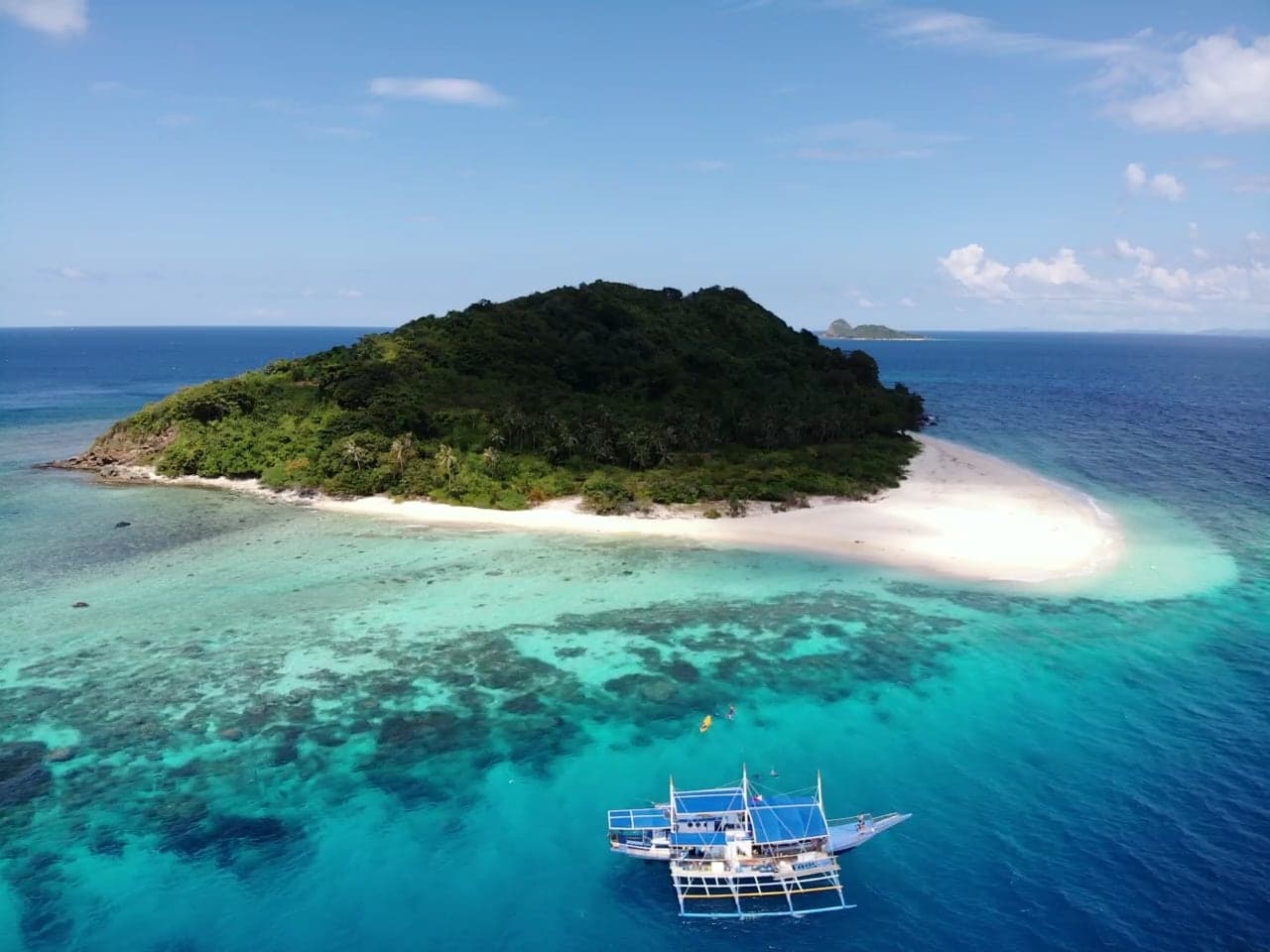 Aerial view of a small tropical island ringed by white sand and reef