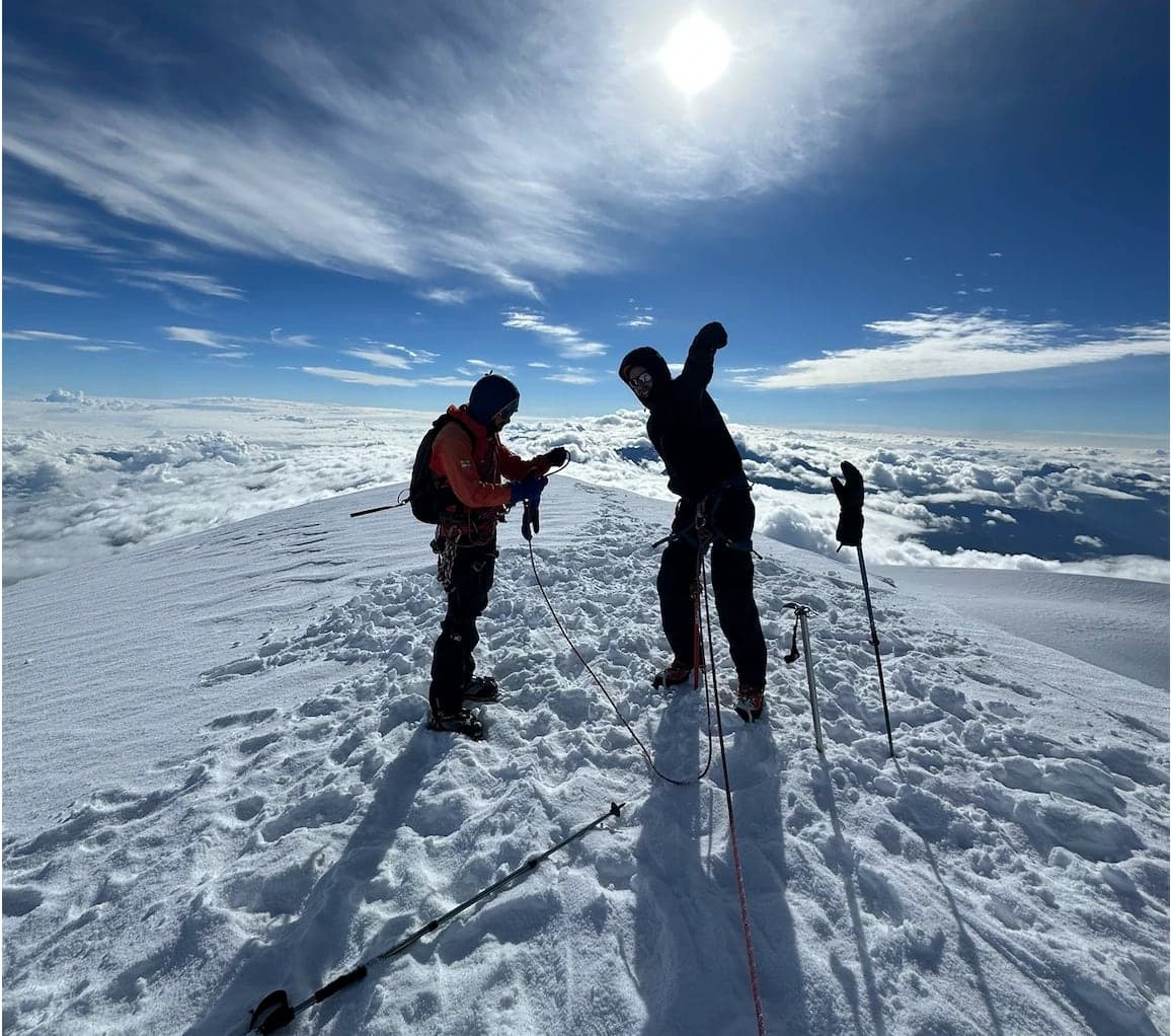 Two climbers on the snowy summit of Mount Kazbek above the clouds